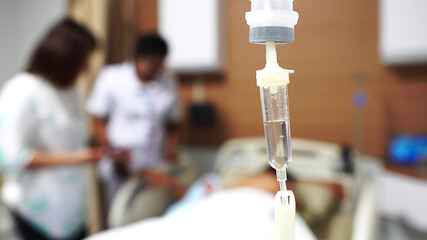 Focus the hanging saline solution with blur patient background.Illness and treatment