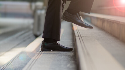 Close-up of businessman's black leather shoes walking up the steps. Business concept