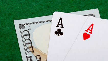 Two aces on a green background and a hundred dollar bill. View from above