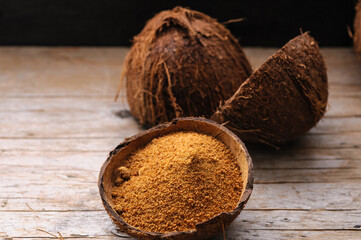 natural granulated coconut sugar in a coconut shell on a wooden background