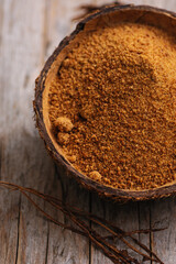 natural granulated coconut sugar in a coconut shell on a wooden background, view from above