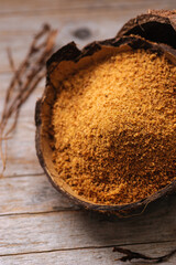natural granulated coconut sugar in a coconut shell on a wooden background, view from above