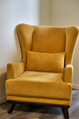 Yellow English chair in the room. A chair with ears and armrests. Classic style. High quality photo