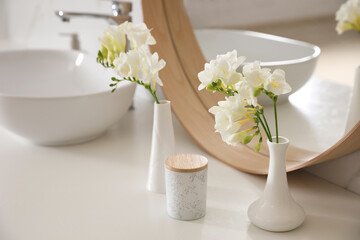 Beautiful white freesia flowers on countertop in bathroom
