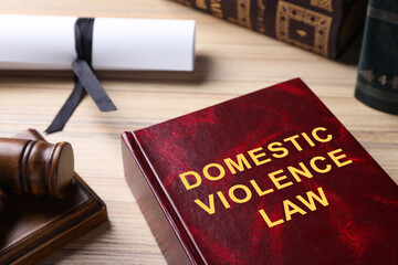 Domestic violence law book on wooden table, closeup