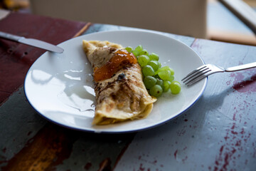 close-up of a white plate with thin pancake and grapes