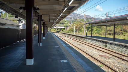 Empty platform at train station with metal sheet roof on clear blue sky background , copy space