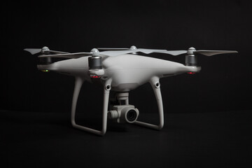 White drone (Quadrocopter) with camera on gimbal on dark background