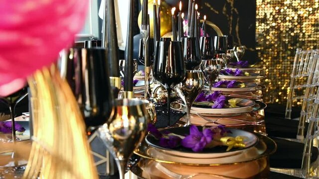 gold Cutlery black wine glasses and black candles on a festive table in the style of a Golden party