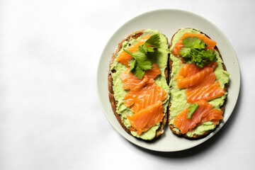 sandwich with guacamole and salmon on a plate on a white background