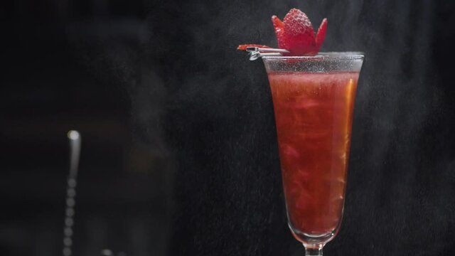 Ready-made Strawberry Rossini Cocktail rotating and slowly moving on slider. Close up bartenders hand sprinkling berry with powdered sugar. Bar drinks series.