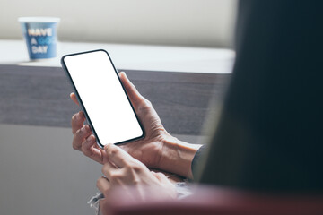 cell phone mockup image blank white screen.woman hand holding texting using mobile on desk at coffee shop.background empty space for advertise.work people contact marketing business,technology