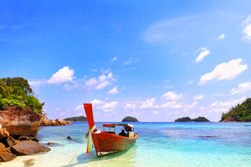 Obraz premium A wooden boat at the beach with blue sea, white cloud in blue sky, nobody and more space for copy paste