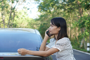 Asian woman Call a mechanic, the car goes out on the road around the forest.             