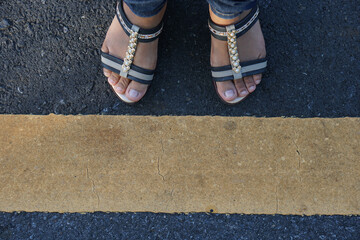 woman's foot on the yellow line of the road