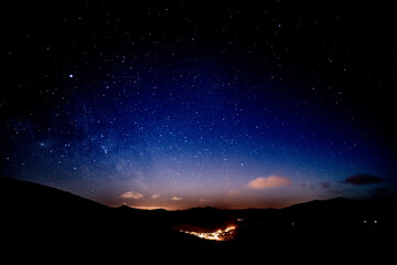 Sternhimmel über beleuchtetem dorf in hügellandschaft