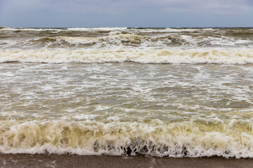Dirty sea waves hitting the beach in stormy weather