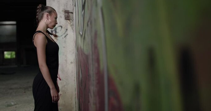 Brutal look of a girl posing at the camera near wall in abandoned building