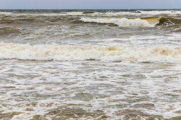 Dirty sea waves hitting the beach in stormy weather