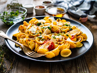 Pasta with parmesan and vegetables on wooden background
