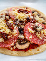 Uncooked margherita pizza on baking paper
