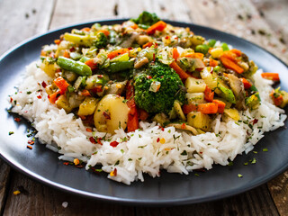 Roast meat, white rice and vegetables on wooden table

