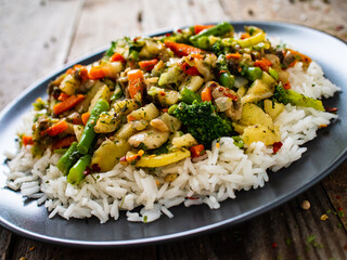 Roast meat, white rice and vegetables on wooden table

