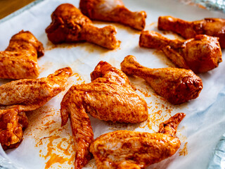 Raw chicken drumsticks and wings on baking paper
