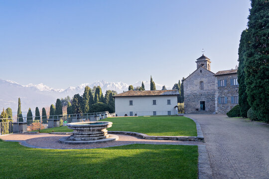 Panoramic view of ancient buildings in Abbey of Piona with beautiful olive groves against Alps mountain in early morning, Italy