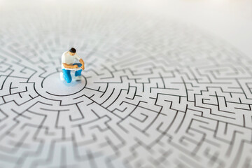 Miniature people : The man writting the book on center of maze : Concepts Troubleshooting Analysis of problems to find solutions.