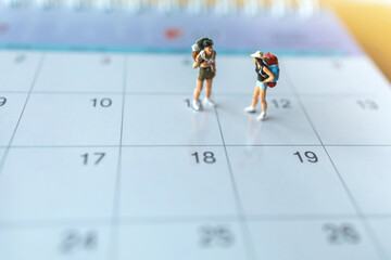 Miniature people: Couple backpackers standing over calendar : Concepts vacation and travelling