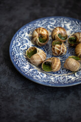 Snails with herbs butter served on beautiful blue vintage plate. Escargot de Bourgogne