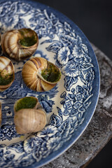 Snails with herbs butter served on beautiful blue vintage plate. Escargot de Bourgogne