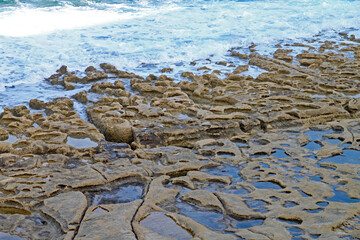 The rock pools in the sandstone shelf on the beach at Sliema, Malta.