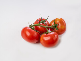 Ripe tomatoes on a branch on white background