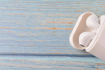 A white wireless headphone on wooden background.