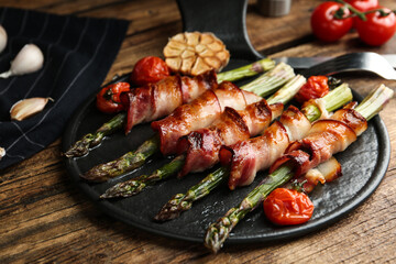 Oven baked asparagus wrapped with bacon on wooden table