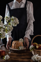 Rustic style apple bundt cake with powdered sugar. Woman holding cake