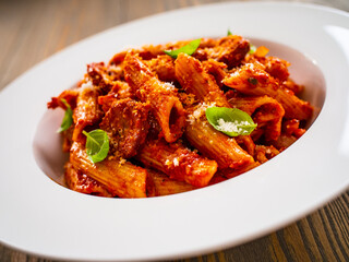 Penne with meat, tomato sauce and vegetables on white background
