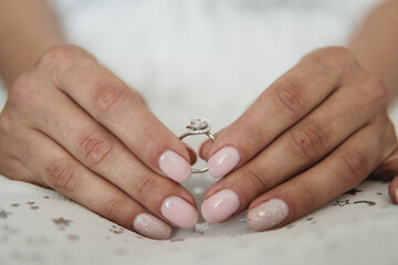 The bride is holding a wedding ring.Close up of fingers with a beautiful delicate festive manicure