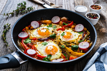 Shakshuka - fried eggs with vegetables in frying pan
