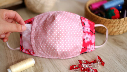 Handmade project DIY face mask made out of red cotton fabirc. A washable fabric mask as mouth cover for extra protection with filter pocket.