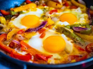 Shakshuka - fried eggs with vegetables in frying pan
