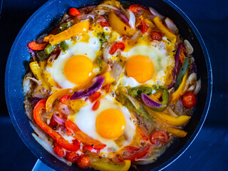Shakshuka - fried eggs with vegetables in frying pan
