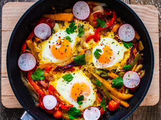 Shakshuka - fried eggs with vegetables in frying pan
