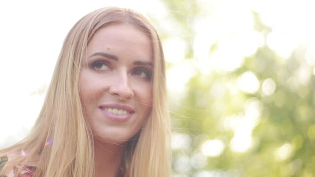 Video clip, blur effect and light fler, a young blonde woman with long hair in a long dress walks in a blossoming apple orchard on a sunny day in spring.