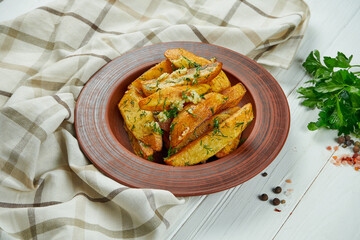 Baked potato in Georgian style with garlic, dill in a ceramic plate on a white wooden background. Close up, selective focus