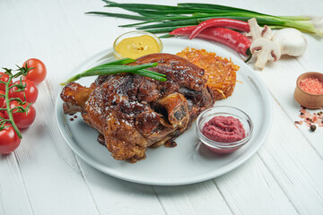 Appetizing baked pork shank in beer and honey with fried cabbage and mustard. Traditional German and Czech beer snack. White wooden background. Ham hock