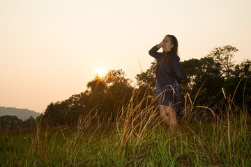 Fototapeta premium Portrait of Asian woman standing in grass field of forest Evening