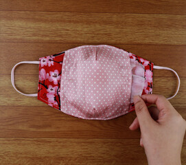 Handmade project DIY face mask made out of red cotton fabirc. A washable fabric mask as mouth cover for extra protection with filter pocket.